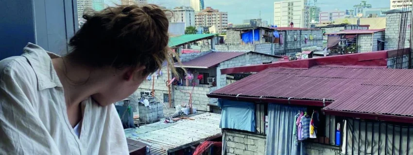 Natalie schaut aus dem Fenster auf einen Slum von Manilla